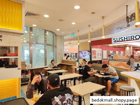 Diners eating inside a bustling restaurant or food court area.
