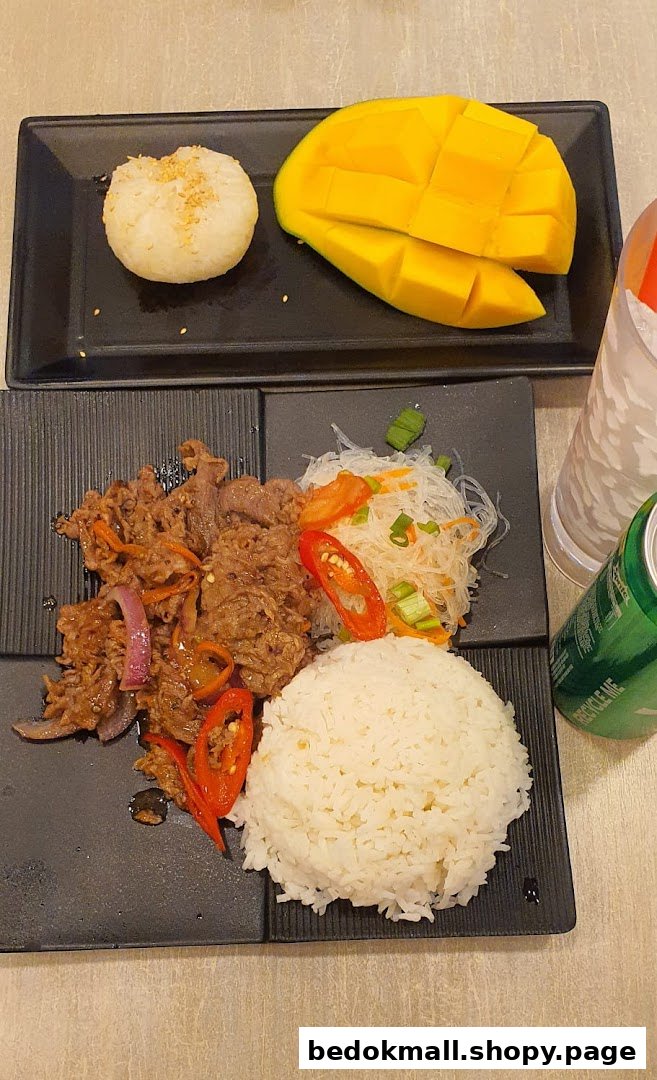 Plates of beef, rice, noodles, mango sticky rice, and a drink on a table.
