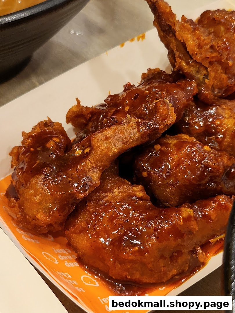 Close-up of saucy fried chicken wings in a white container.