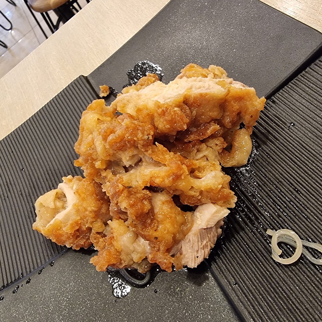 Close-up of crispy fried chicken served on a black textured plate.