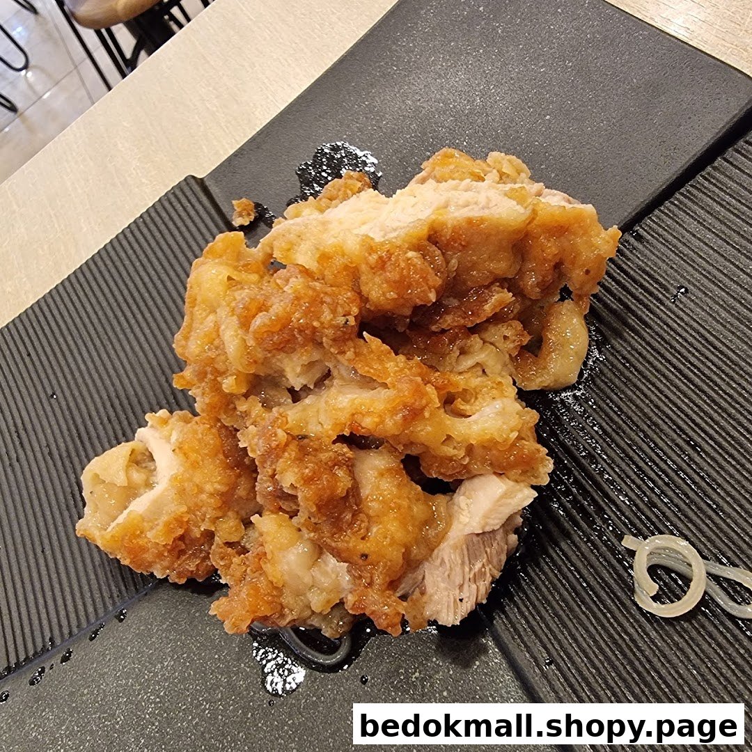 Close-up of crispy fried chicken served on a black textured plate.