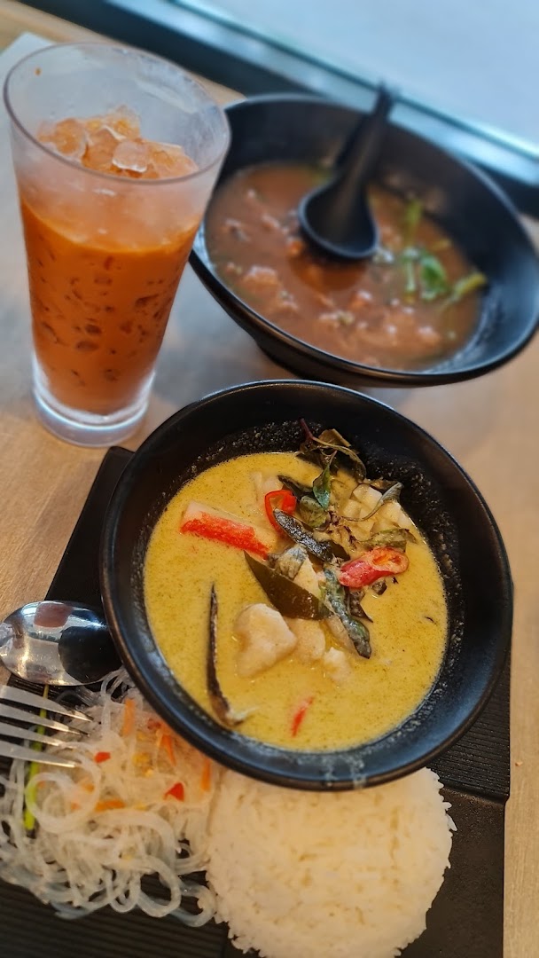 Thai green curry, rice, soup, and iced tea on a table.