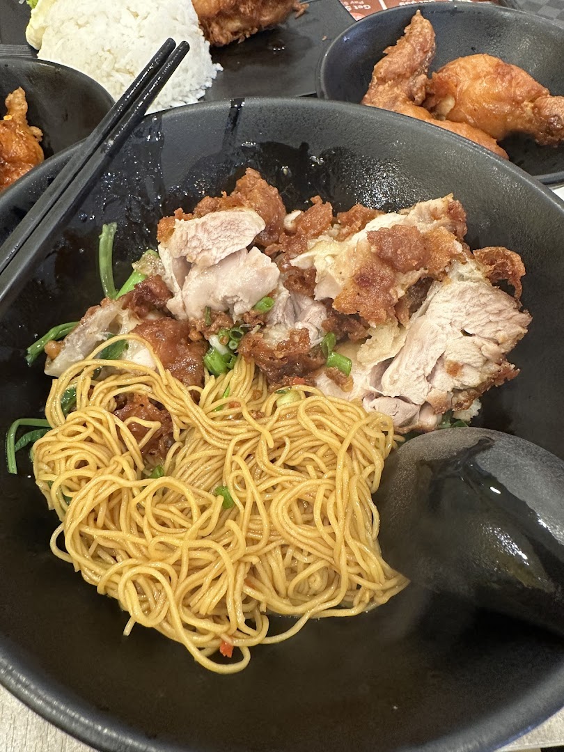 A close-up of a bowl of noodles with crispy pork and chicken.