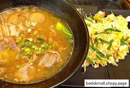 A bowl of soup with meat and a plate of pad thai on a black tray.