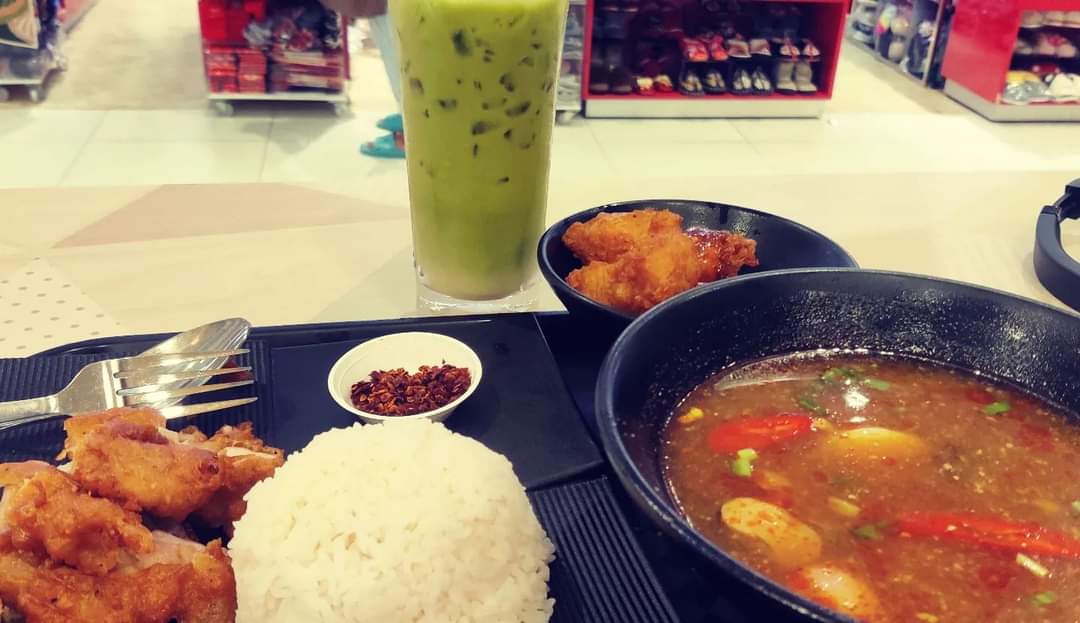 A meal with rice, fried chicken, soup, and a green drink on a table.