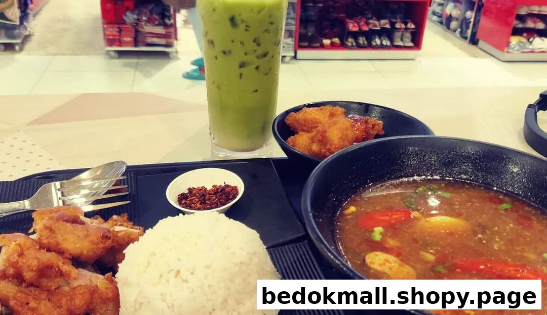 A meal with rice, fried chicken, soup, and a green drink on a table.