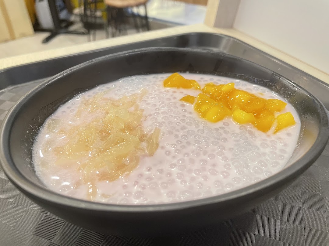 A bowl of Thai dessert with tapioca pearls, mango, and pomelo.