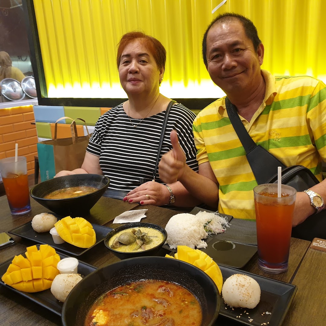 Two people dining at a table with multiple Thai dishes.