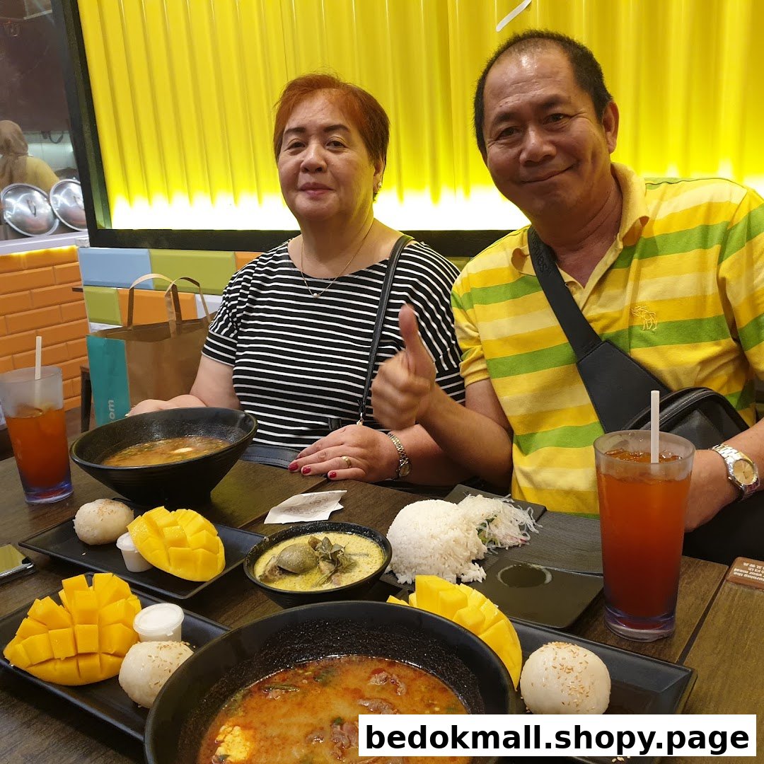 Two people dining at a table with multiple Thai dishes.