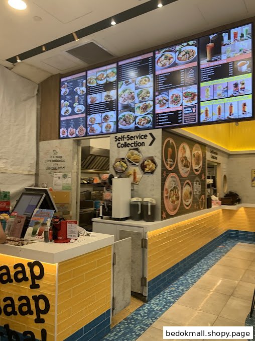 Interior view of a Thai food shop with a large digital menu board and counter.