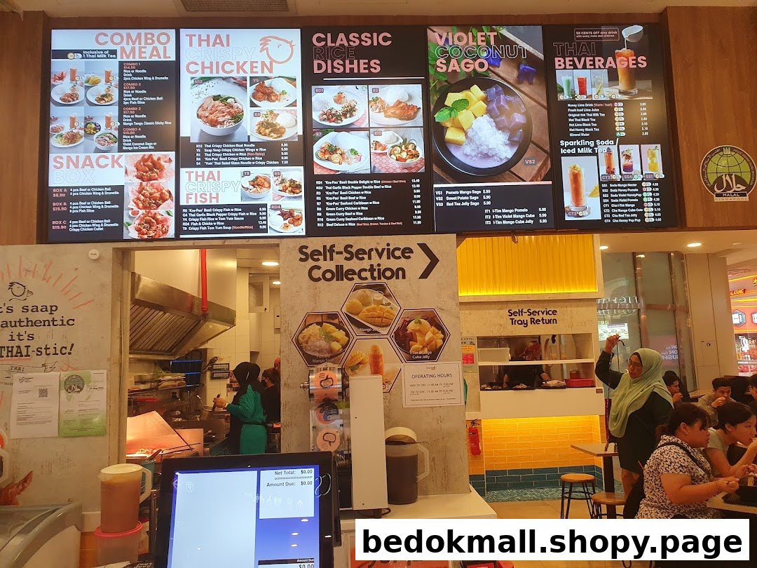 Large menu board above a busy Thai restaurant kitchen and dining area.