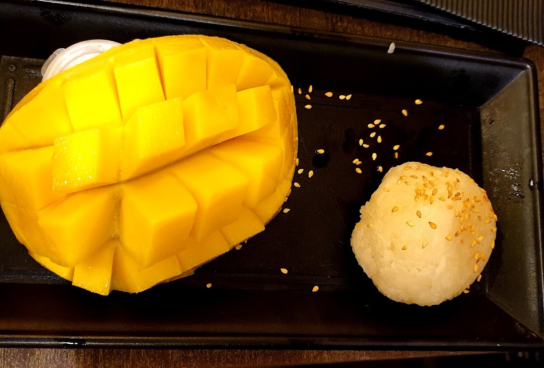 A plate of mango sticky rice dessert with sesame seeds.
