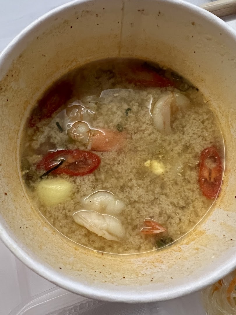 Bowl of Thai soup with shrimp, tomatoes, and other ingredients.