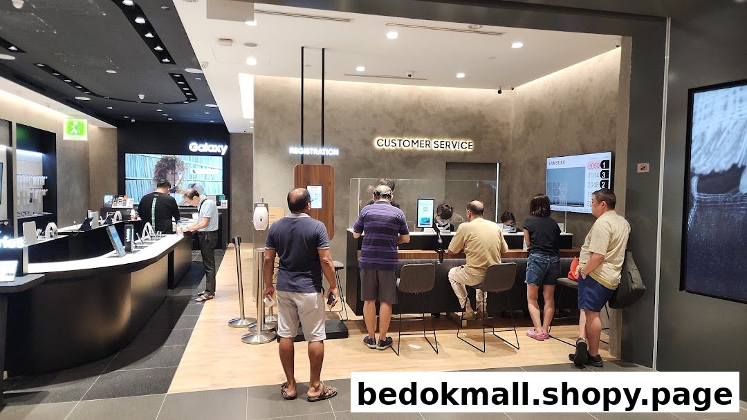 Interior view of a Samsung store with customers at product displays and service counters.