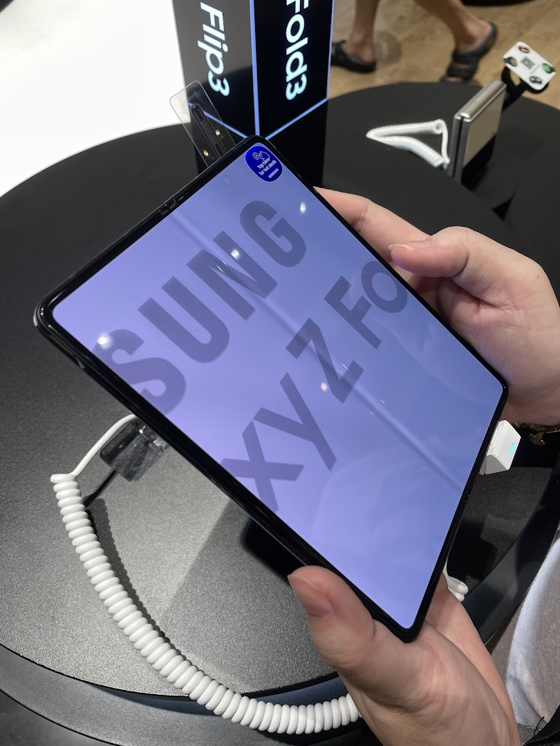 Person holding a Samsung Galaxy Z Fold phone in a retail store.