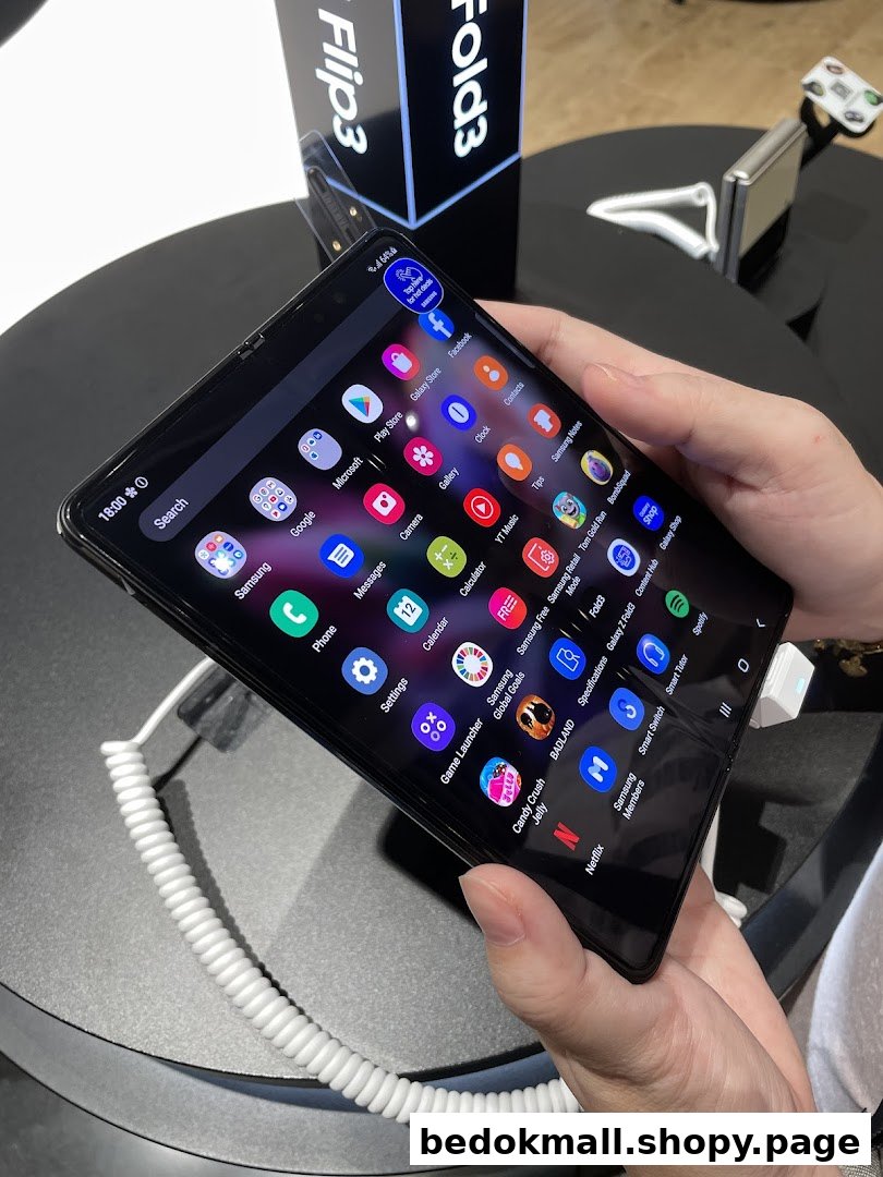 Person holding a Samsung foldable phone displaying app icons in a retail store.