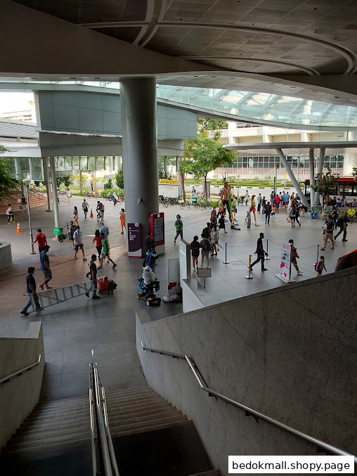 View of a busy modern public concourse with people and stairs.