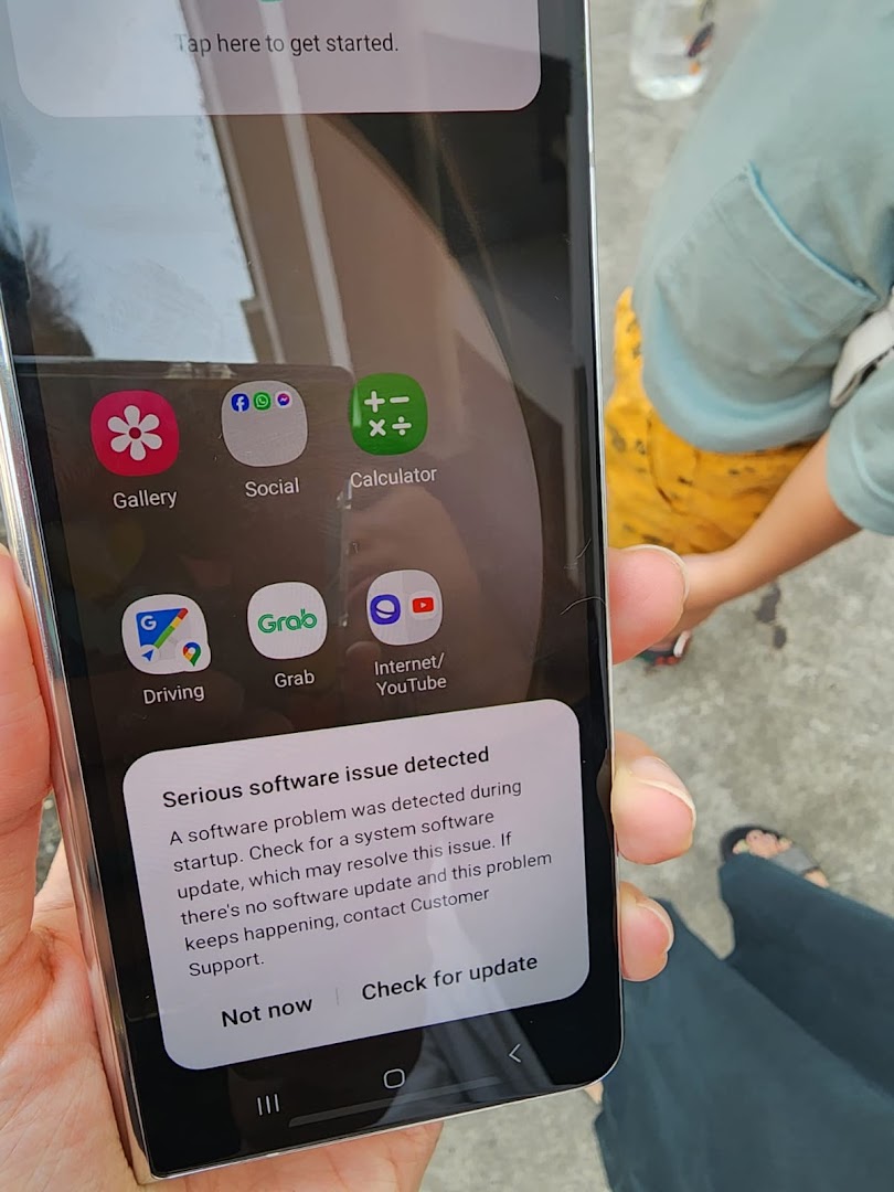 A hand holding a smartphone displaying a software error message.
