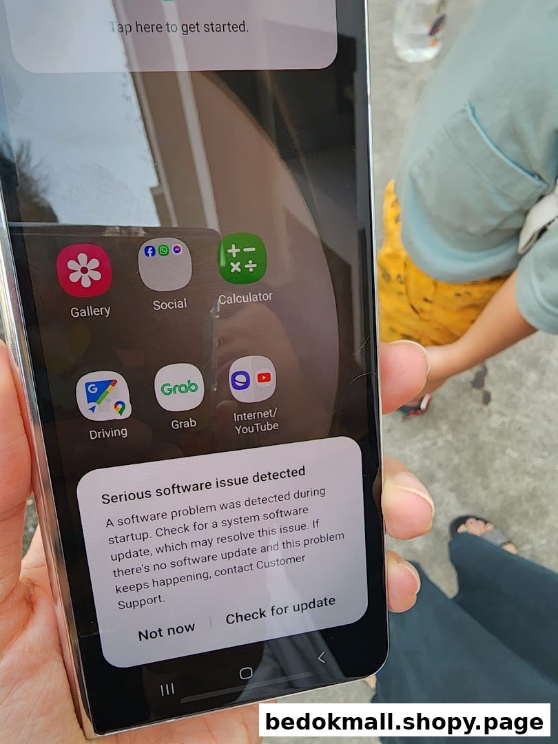 A hand holding a smartphone displaying a software error message.