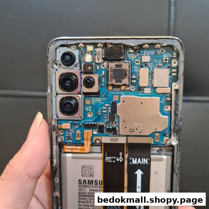 A hand holds a disassembled smartphone, revealing its internal circuit board, cameras, and battery.