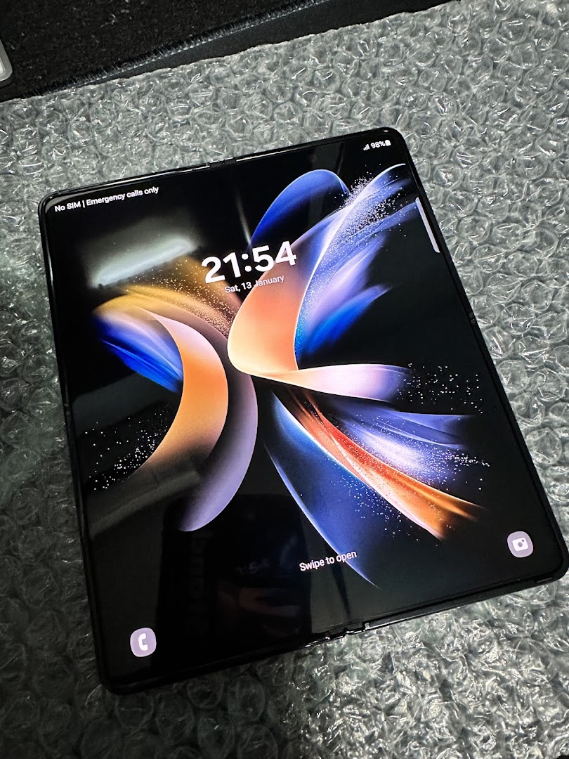 A Samsung foldable phone displaying its lock screen on a textured surface.