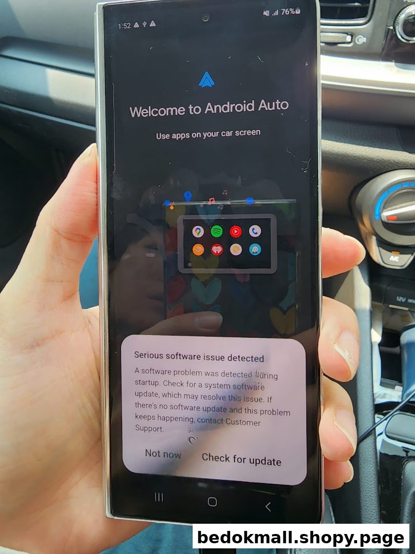Hand holding a smartphone displaying an Android Auto screen and software error in a car.