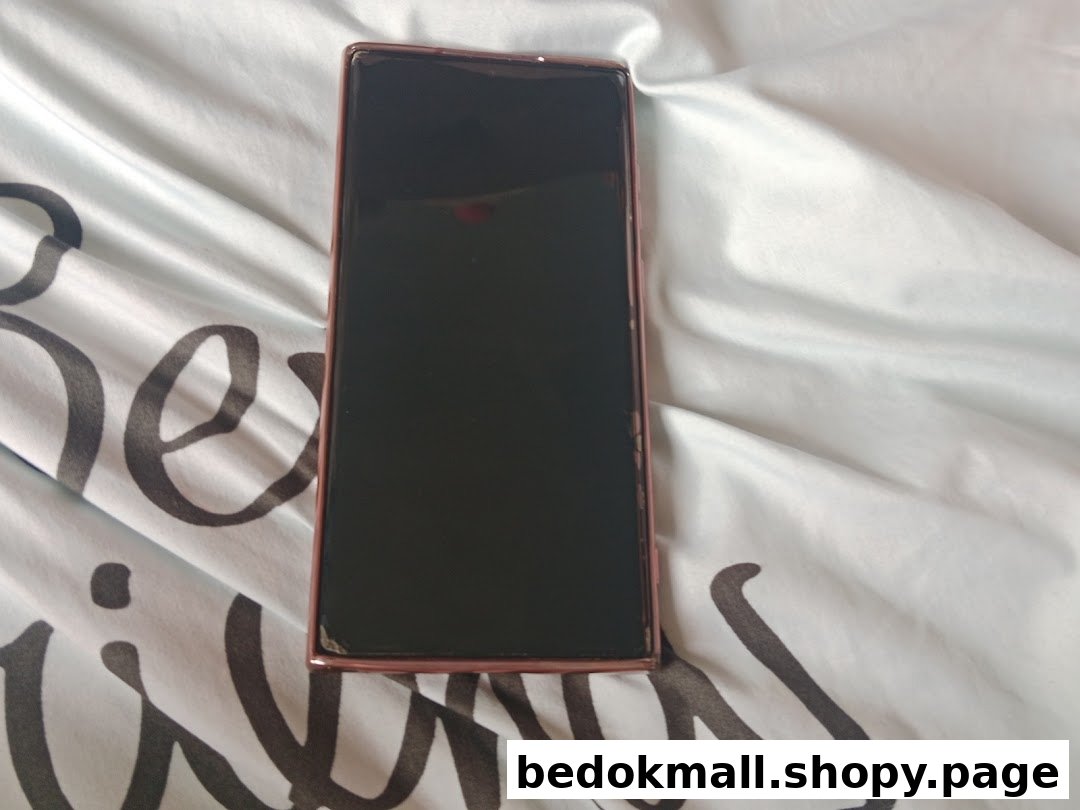 A smartphone with a dark screen and rose gold frame on patterned fabric.