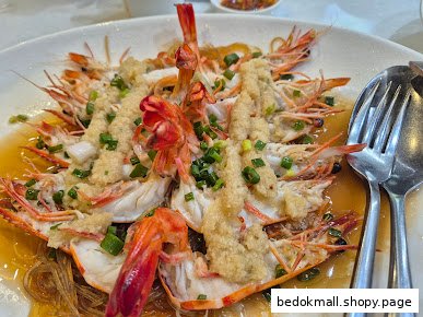 A large plate of steamed prawns with garlic, vermicelli, and green onions.