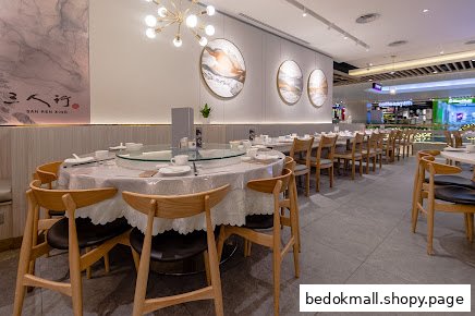 Interior view of a restaurant with round tables, chairs, and decorative wall art.
