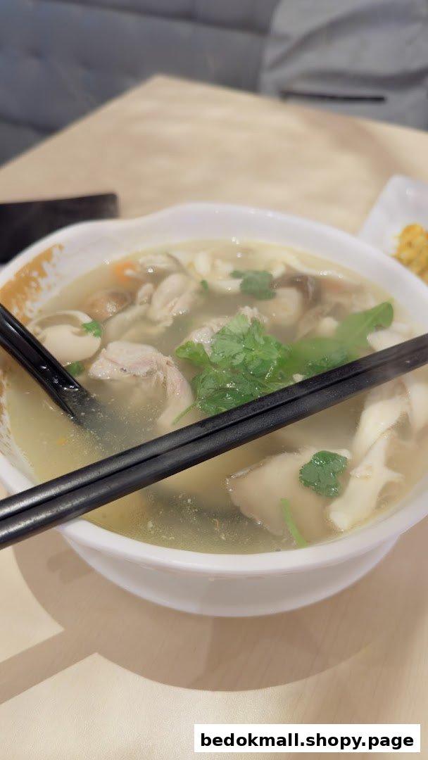 A steaming bowl of soup with meat, mushrooms, and herbs on a table.