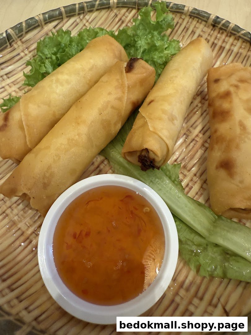 Fried spring rolls with dipping sauce and lettuce on a woven plate.