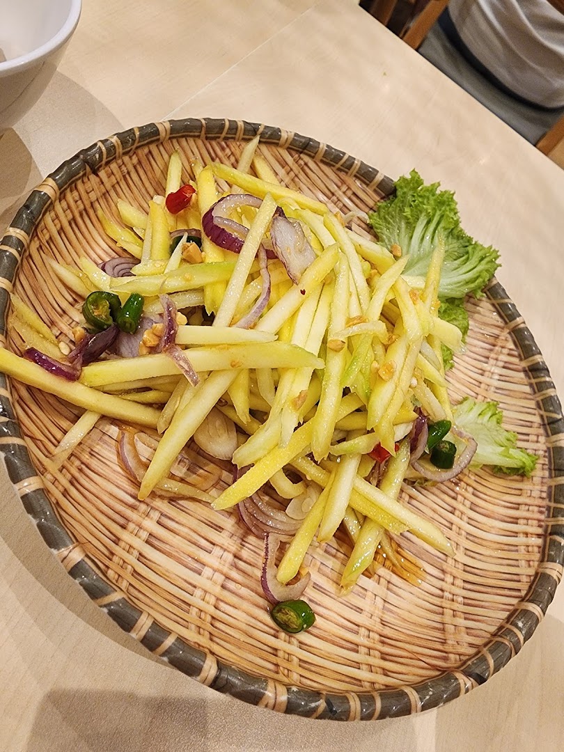 A plate of mango salad with red onions and chilies on a woven tray.