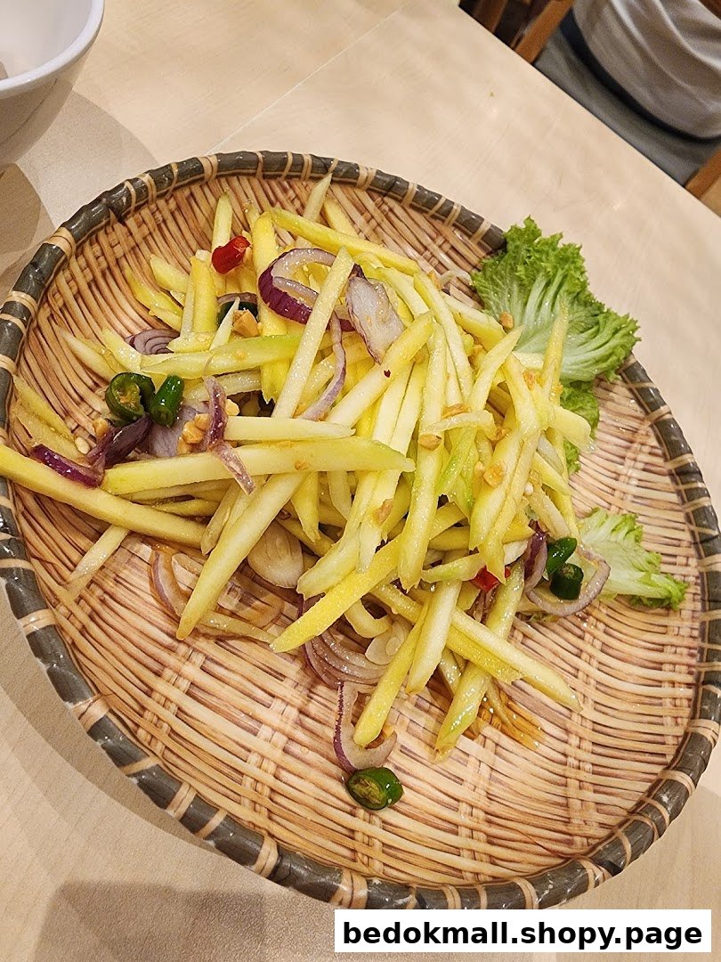 A plate of mango salad with red onions and chilies on a woven tray.