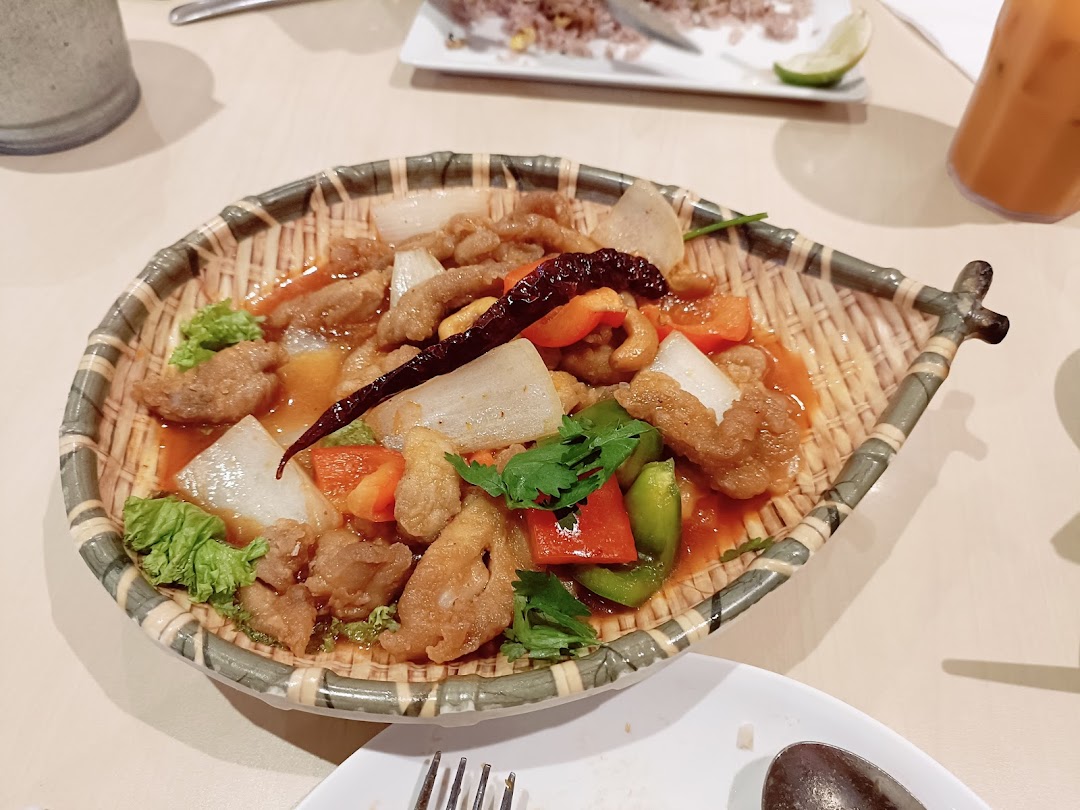 A dish of sweet and sour chicken with vegetables on a woven plate.