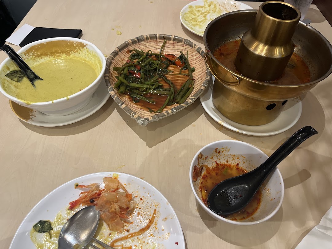 Table with various Thai dishes, including hot pot, curry, and eaten shrimp.