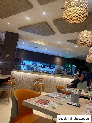 Interior view of a restaurant with tables, chairs, and a counter area.
