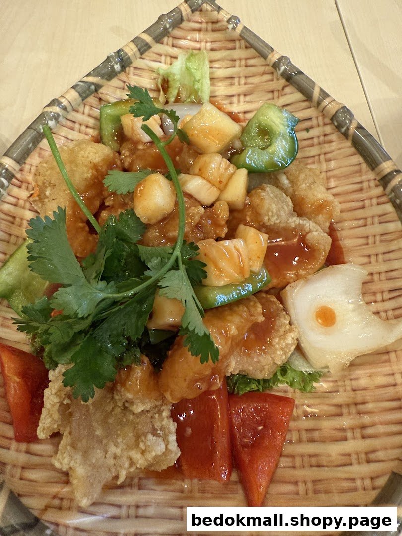A sweet and sour dish with fried items and vegetables on a woven plate.