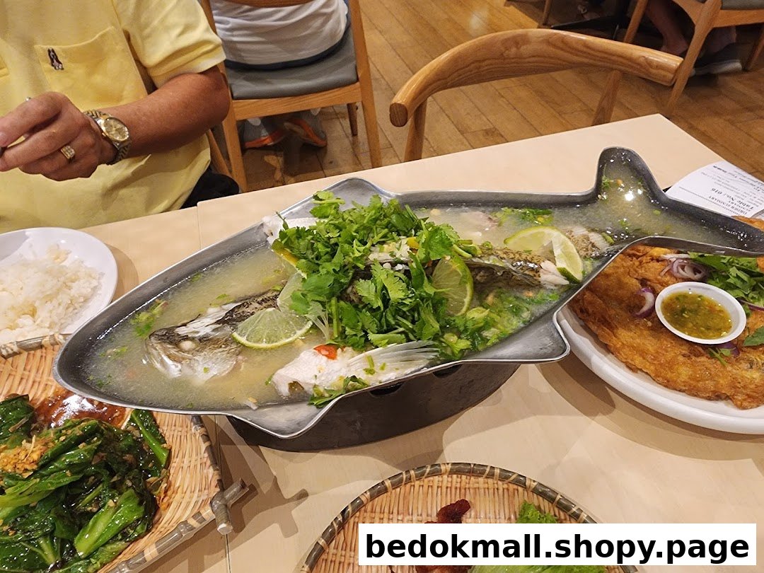 Table with steamed fish, omelet, and other dishes at a restaurant.
