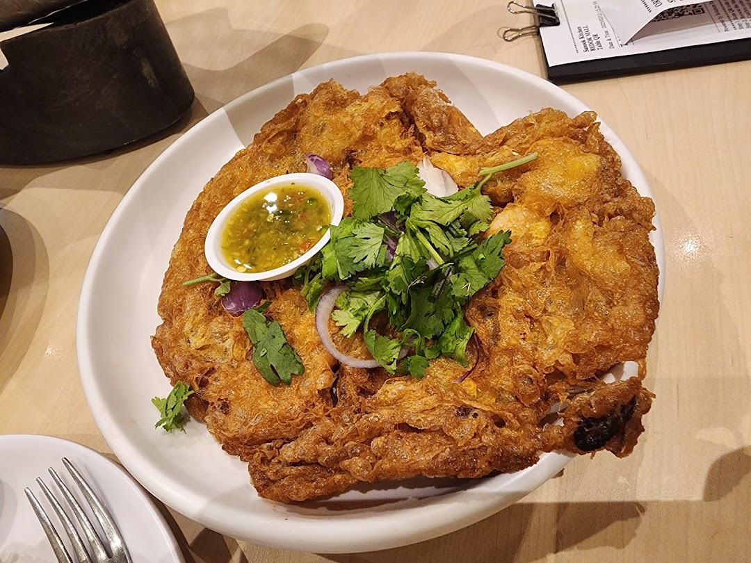A plate of crispy fried omelet or fritter with sauce and fresh herbs.
