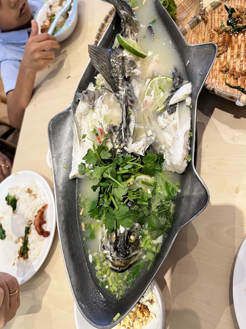 Steamed fish with lime and herbs in a fish-shaped platter on a table.