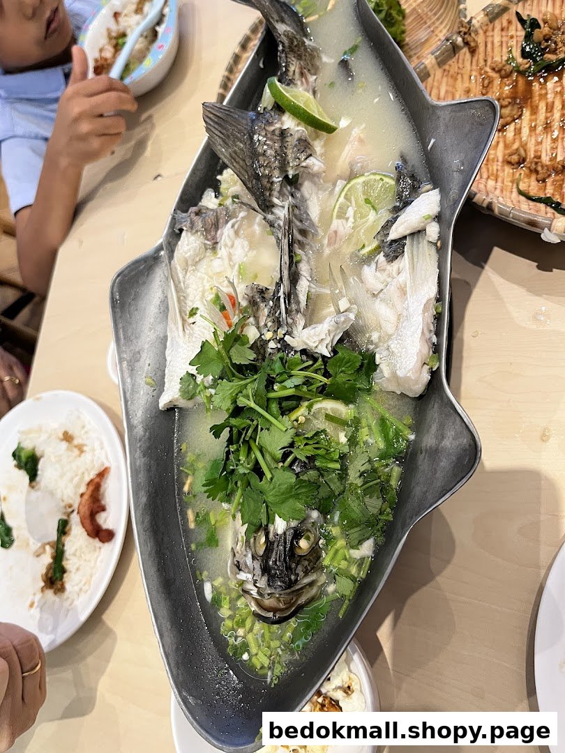 Steamed fish with lime and herbs in a fish-shaped platter on a table.