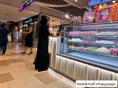 Interior view of a fruit and juice shop with a display counter and customers.