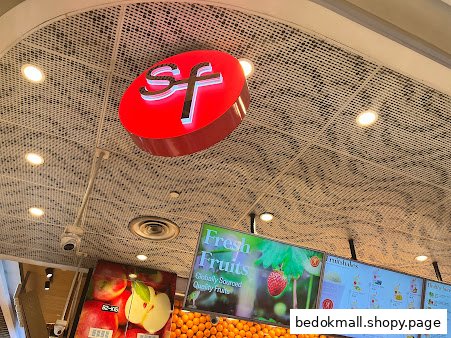 Interior view of a fruit shop with SF logo and digital displays.