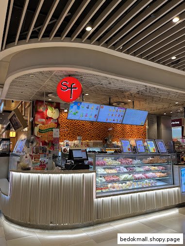 A fruit and juice shop interior with a display counter and digital menus.