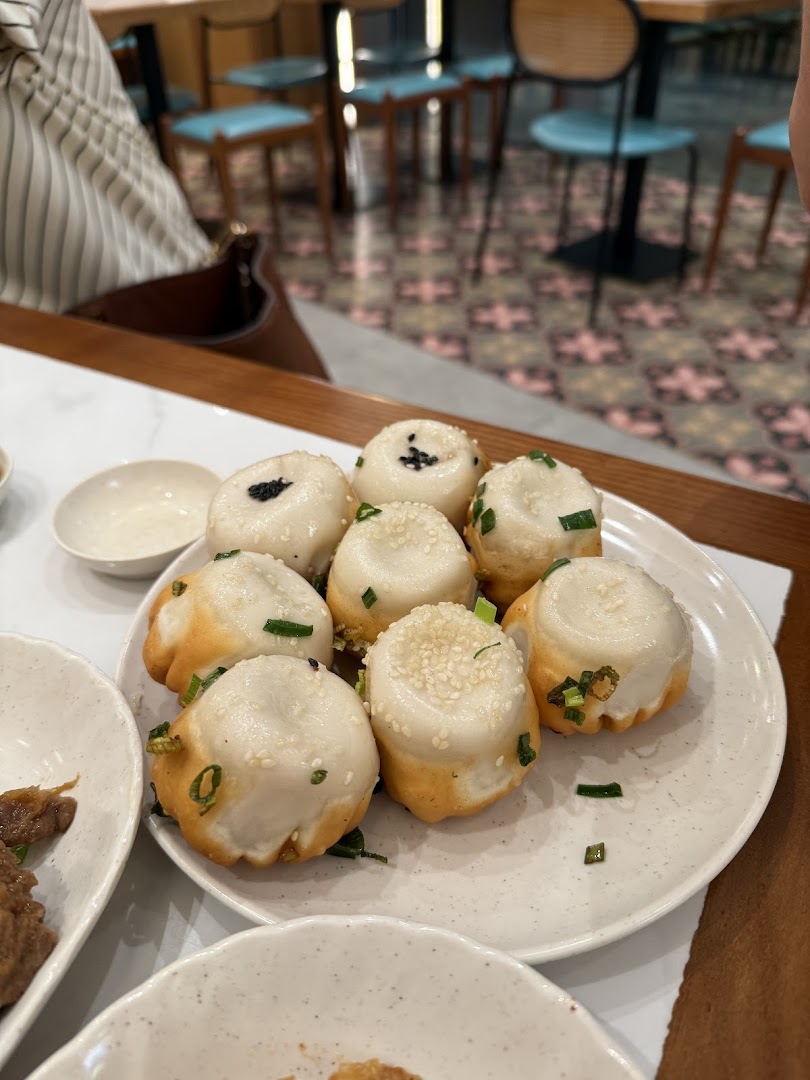 Plate of pan-fried buns with restaurant interior in the background.