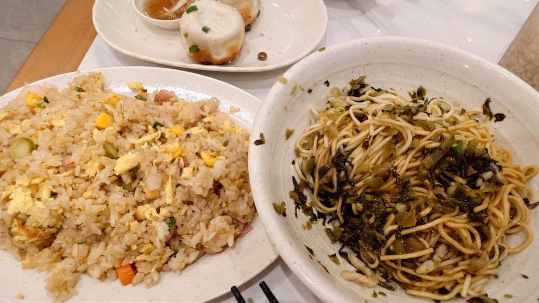 Plates of fried rice, noodles, and pan-fried buns on a table.