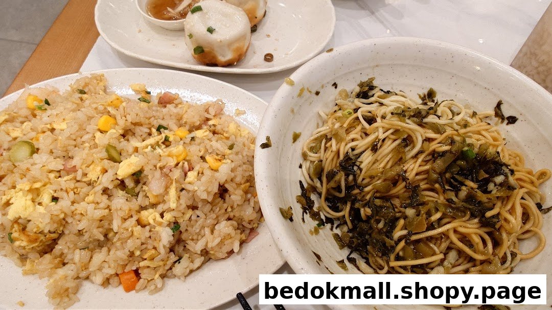 Plates of fried rice, noodles, and pan-fried buns on a table.