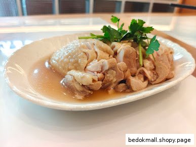 A plate of cooked chicken in sauce, garnished with fresh herbs.