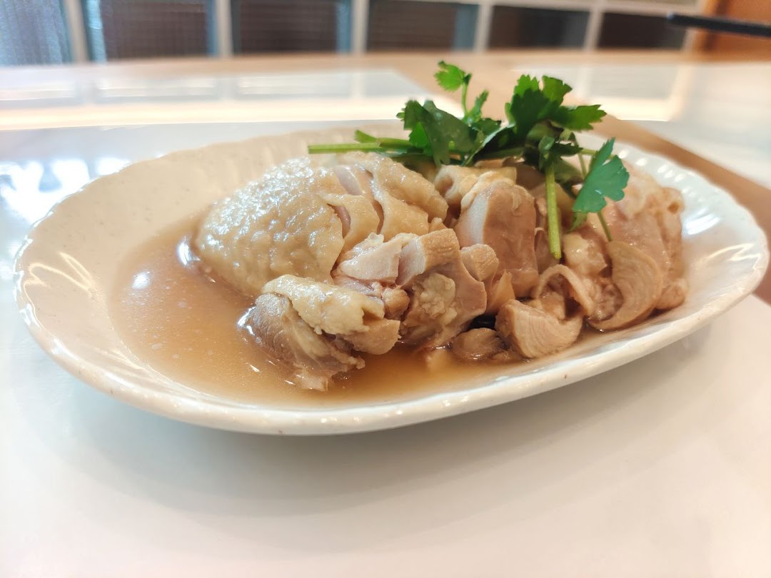 A plate of cooked chicken with sauce and green garnish.