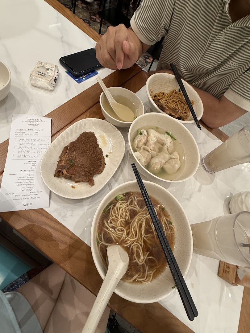 Table with multiple bowls of food, drinks, and a receipt in a restaurant.